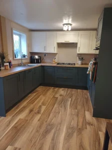 Kitchen with dark cabinets, gas stove, wooden flooring, wooden worktop, bright lighting, and a window letting in natural light.