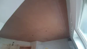 Close-up view of a skimmed ceiling with placeholder holes for electrical fixtures.