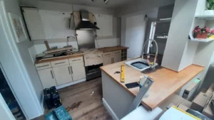 Partially renovated kitchen with uninstalled cabinets, renovation tools, and a work-in-progress countertop with a sink.