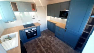 Kitchen with blue cabinets, wooden countertop, built-in oven, and an open layout featuring a door.