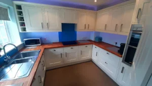 Bright kitchen with white cabinets, wooden countertop, stainless steel sink, and modern appliances under soft ambient lighting.