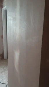 Skimmed interior wall of a room, with a doorway visible in the background.