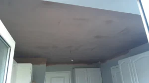 Partial view of a room with skimmed ceiling, exposed wiring, and white doors.