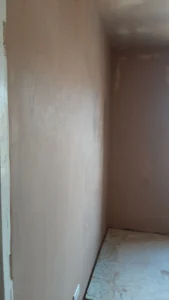Partial view of a room with skimmed ceiling and walls, and a bare floor.